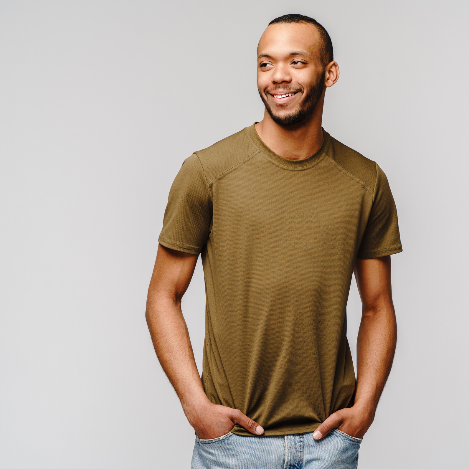 Joyful Friendly African-American Young Man in Green T-Shirt over Light Grey Background with Copy Space