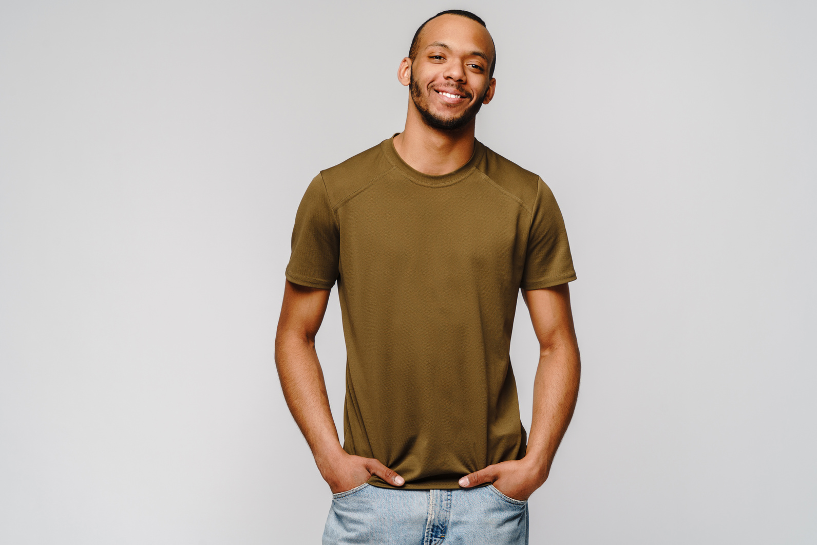Joyful Friendly African-American Young Man in Green T-Shirt over Light Grey Background with Copy Space